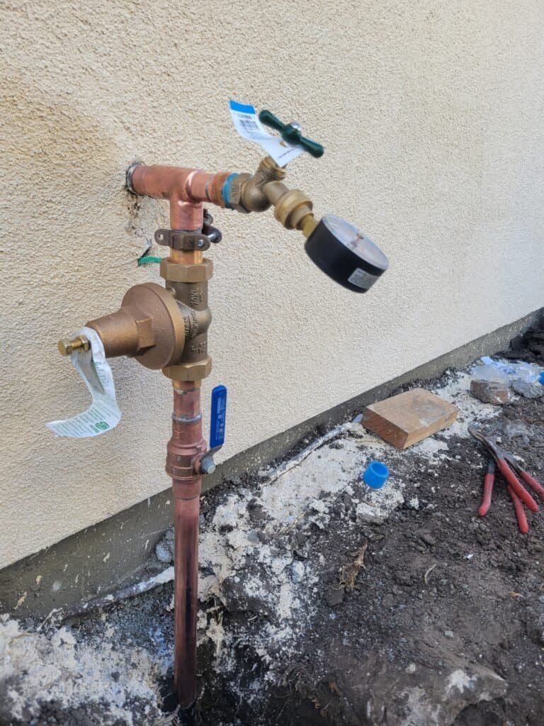 Outdoor water meter with shut-off valve and pressure gauge for leak detection and water management.