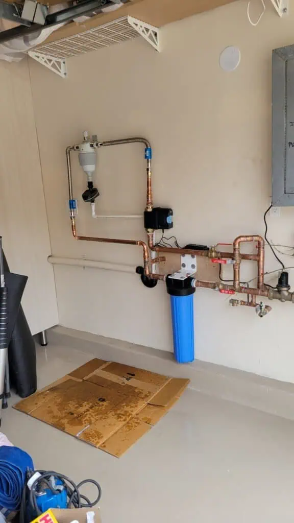 Water filtration system with copper pipes and blue filter housing for clean, safe drinking water.