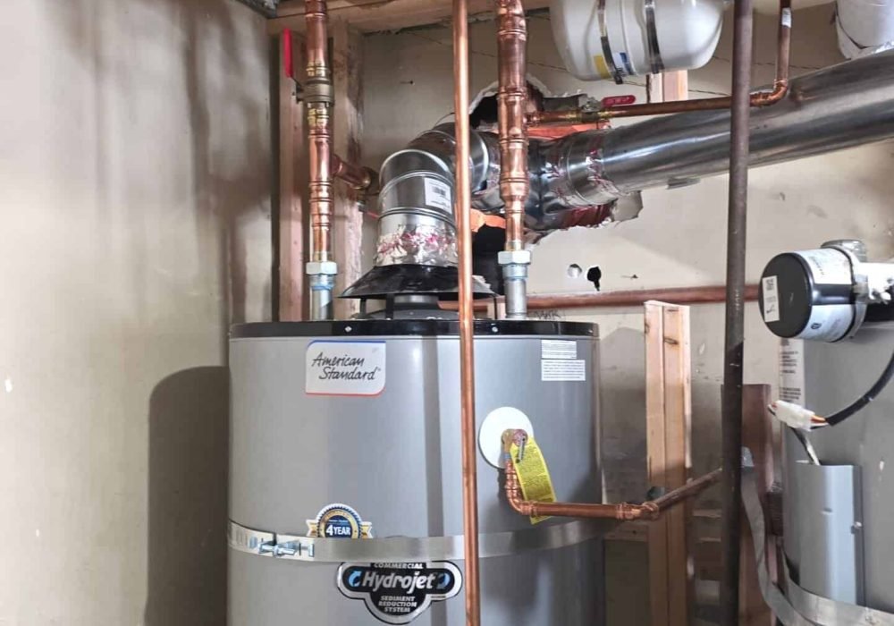 Water heater with copper and PVC piping in a residential basement.