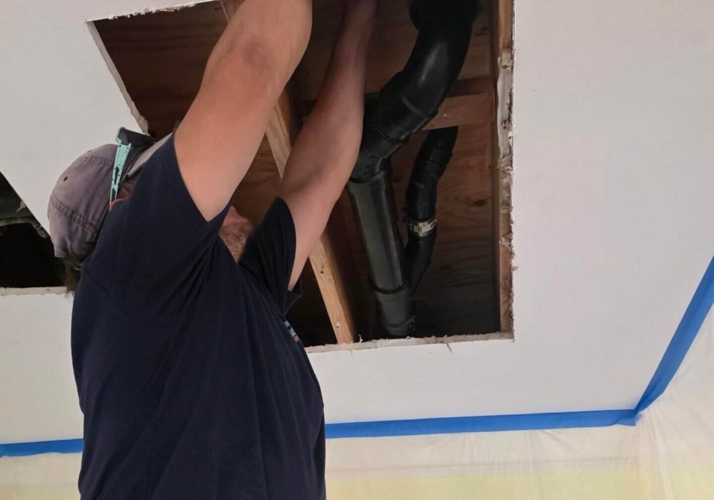 Professional plumber repairing ceiling pipes in a home.